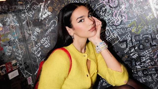 Dua Lipa poses in a yellow cardigan while on tour in Japan