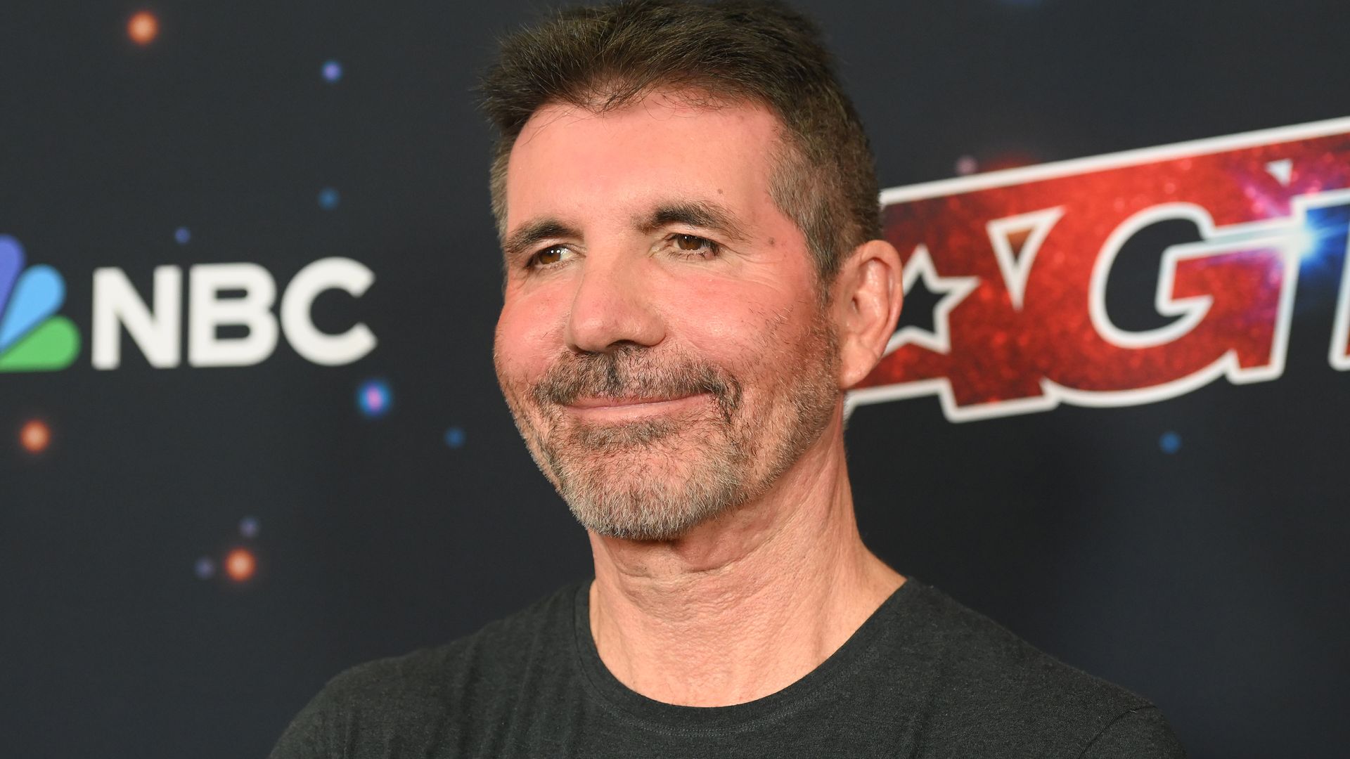 Simon Cowell smiling in a black top