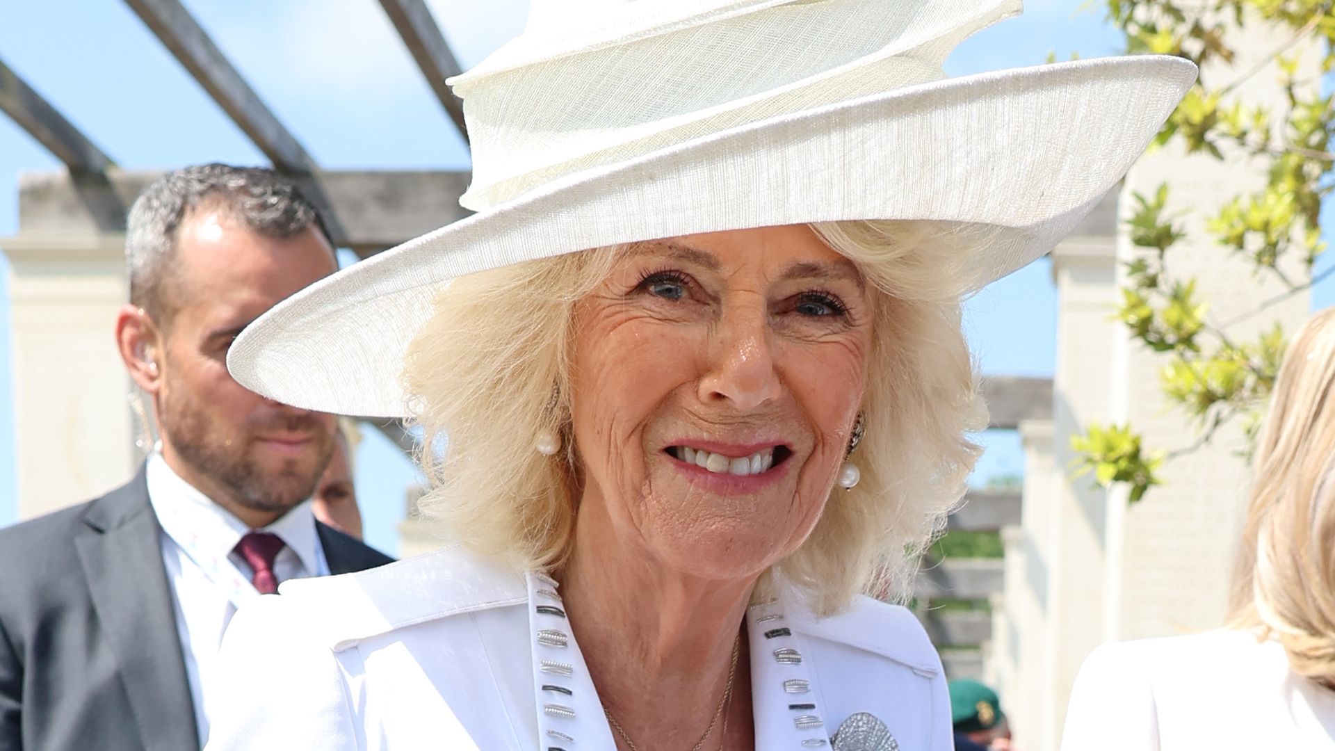 Queen Camilla in a white dress and hat