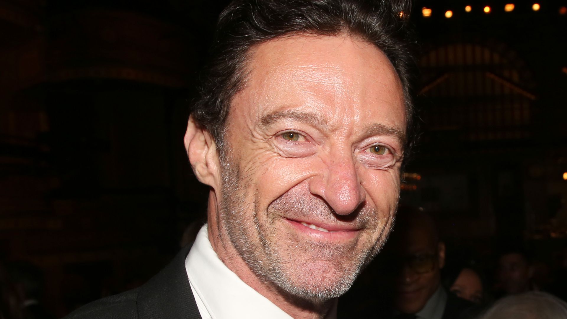 photo of hugh jackman smiling while wearing a black suit and tie