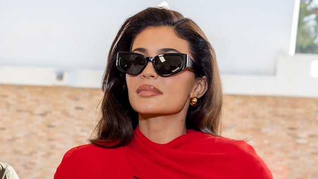 Kylie Jenner attends the "Les Sculptures" Jacquemus' Fashion Show in a red dress and black sunglasses