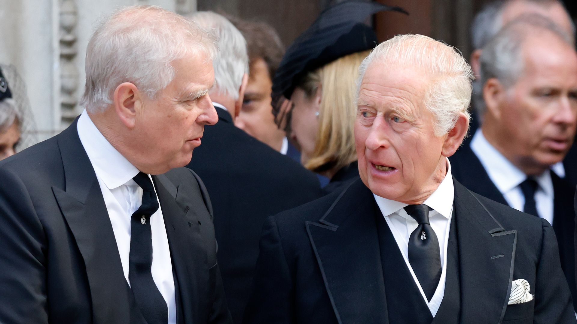 Prince Andrew, Duke of York and King Charles III chatting in black suits