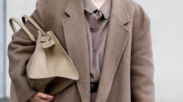 Influencer Maria Barteczko, wearing a brown oversized long wool coat by Zara, a brown v-neck cashmere knit sweater by Soft Goat, brown wide leg belted pantsby Arket, a brown Margaux top-handle bag by The Row and black oversized Aviator glasses by Victoria Beckham