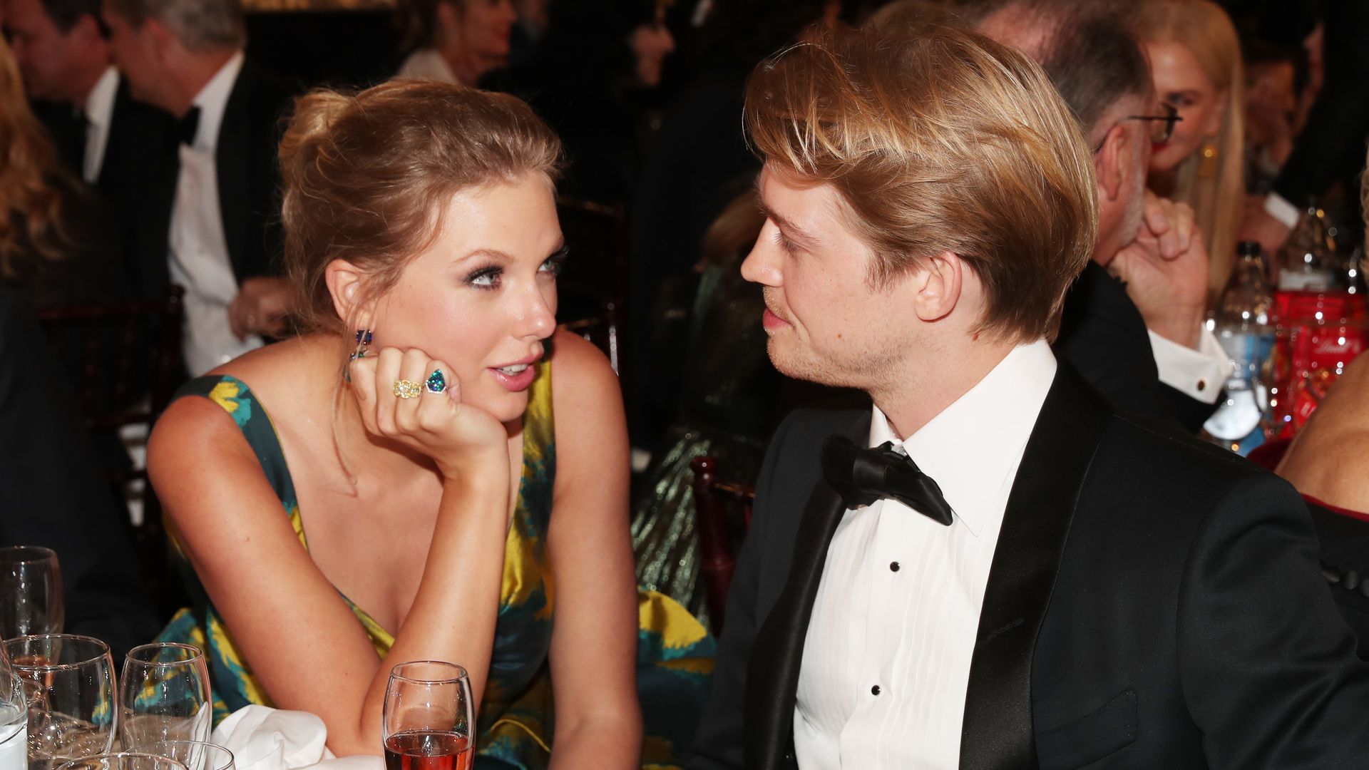Taylor and Joe at an awards ceremony sat talking and looking at each other lovingly
