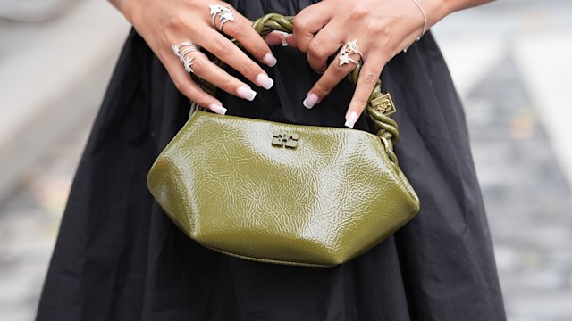  A guest wears black flowy skirt, silver star rings, silver bracelet, shiny dark green olive Ganni recycled leather bag, outside Ganni, outside Ganni, during the Paris Fashion Week Spring/Summer 2025 on September 24, 2024 in Paris, France. (Photo by Edward Berthelot/Getty Images)