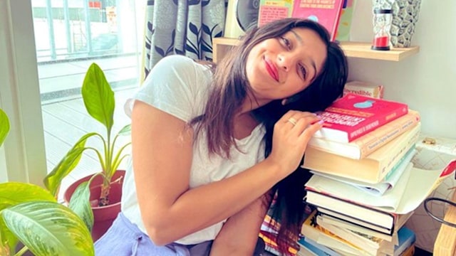 Woman leaning on a pile of books