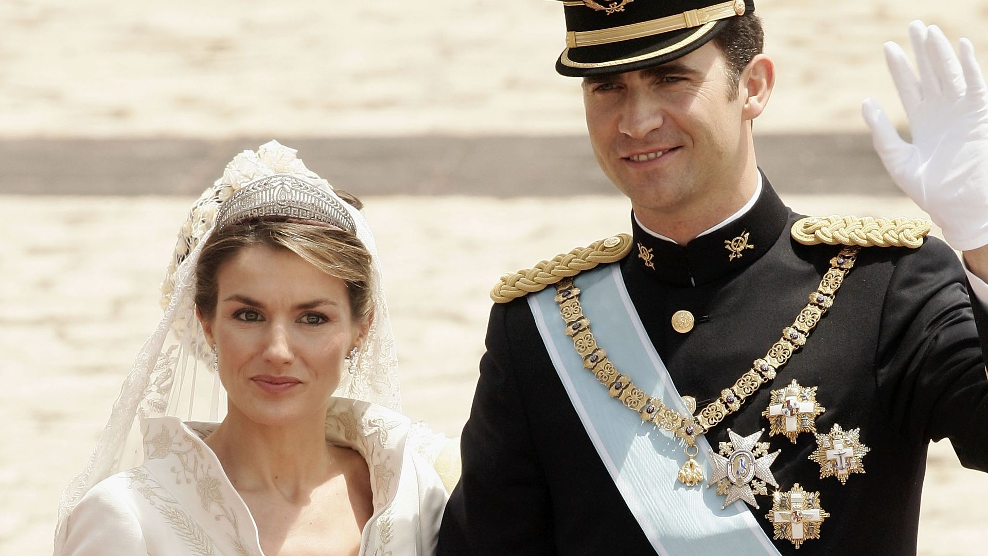 Queen Letizia in her wedding dress next to King Felipe waving