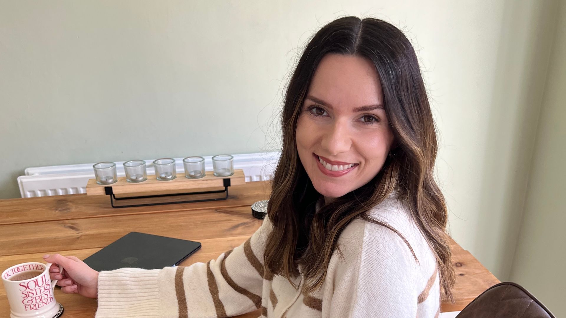woman sat at table with laptop and cup 