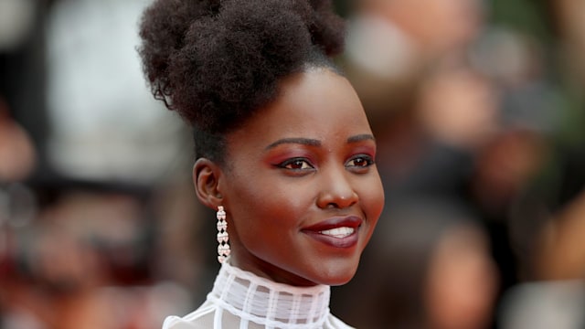 Lupita Nyong'o in a white dress with drop earrings on the red carpet