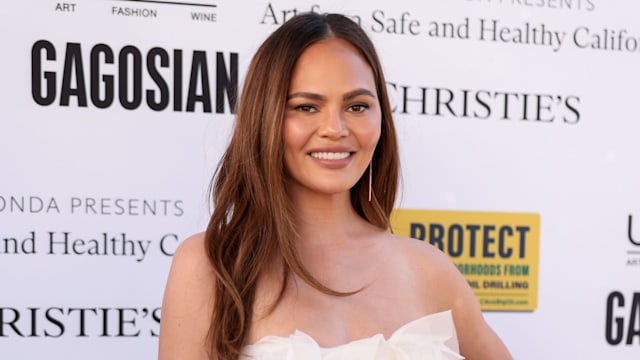 Chrissy smiling in white crop and skirt