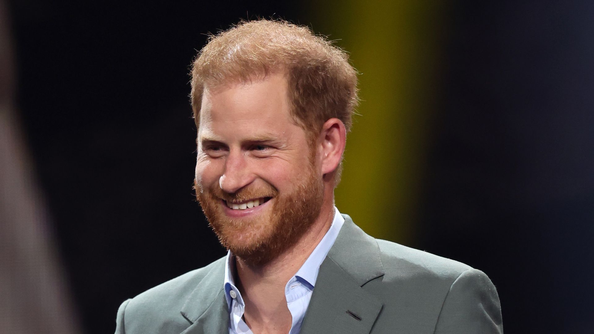 Prince Harry in grey suit holding a microphone