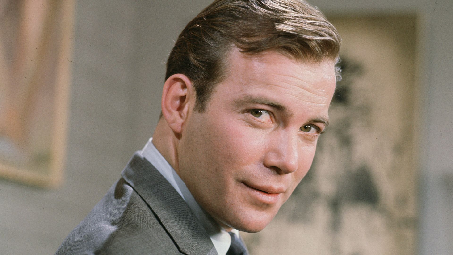 William Shatner throwback looking suave over his shoulder in a suit and tie