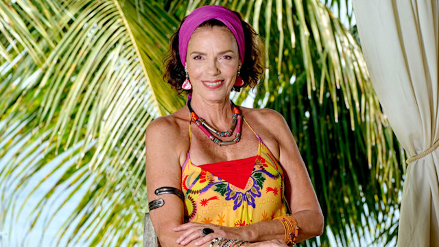 Woman dressed in colourful dress in front of palm tree