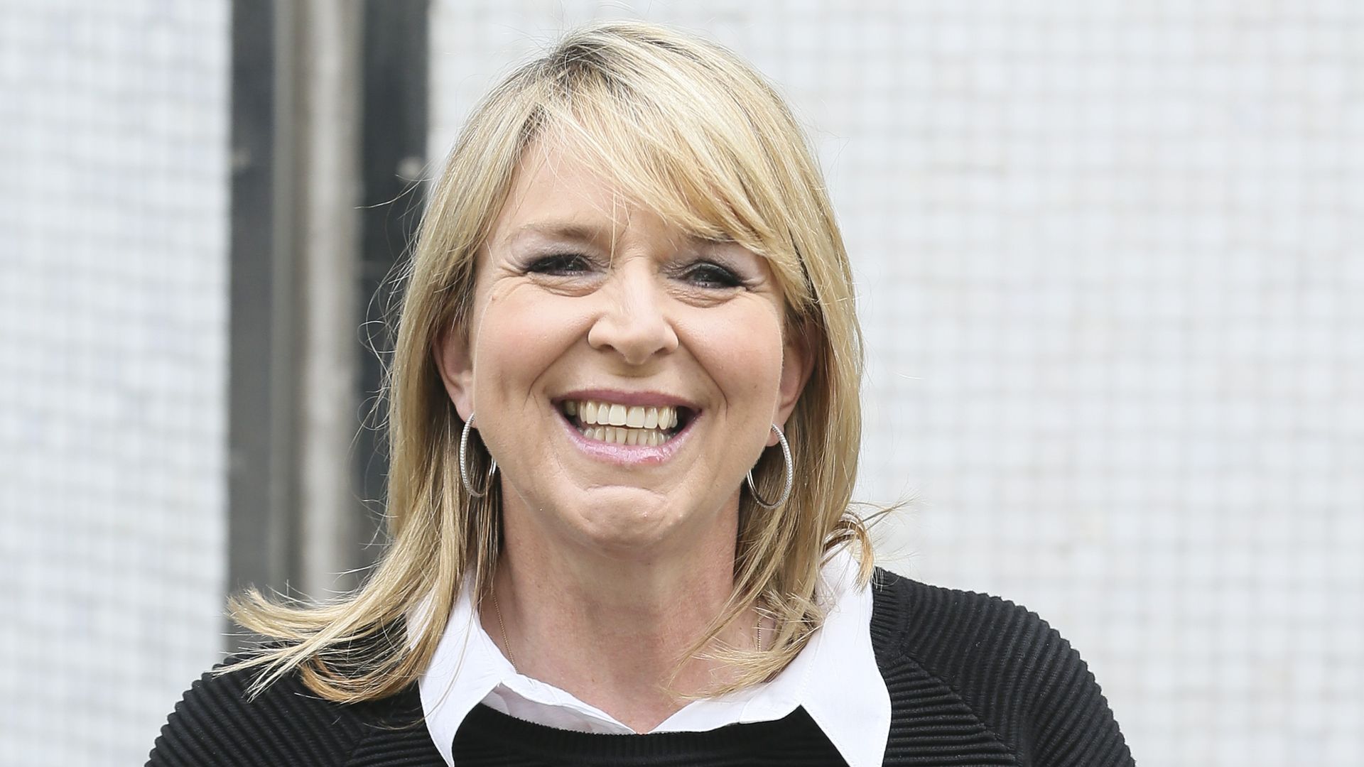 Fern Britton smiling and holding her book