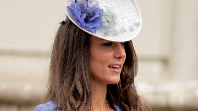 Kate Middleton in a blue dress with her hands up 