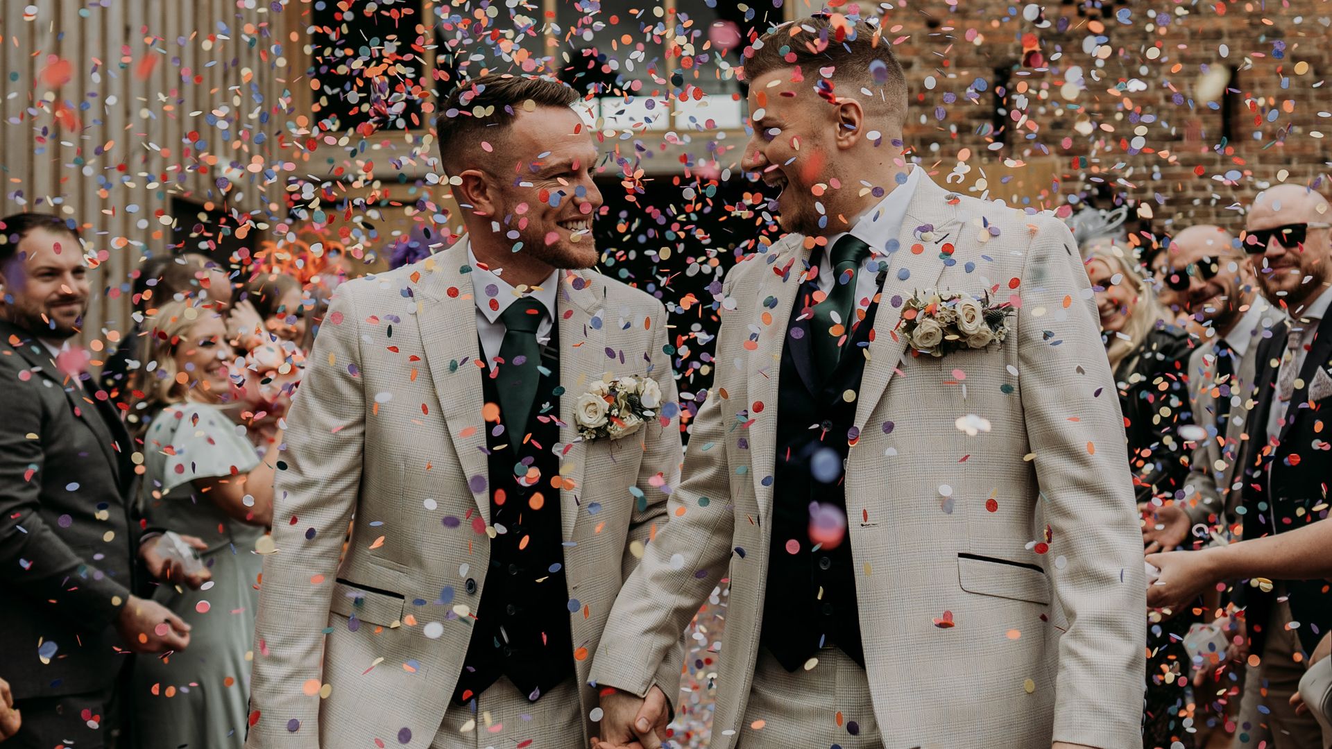 The grooms having confetti thrown over them