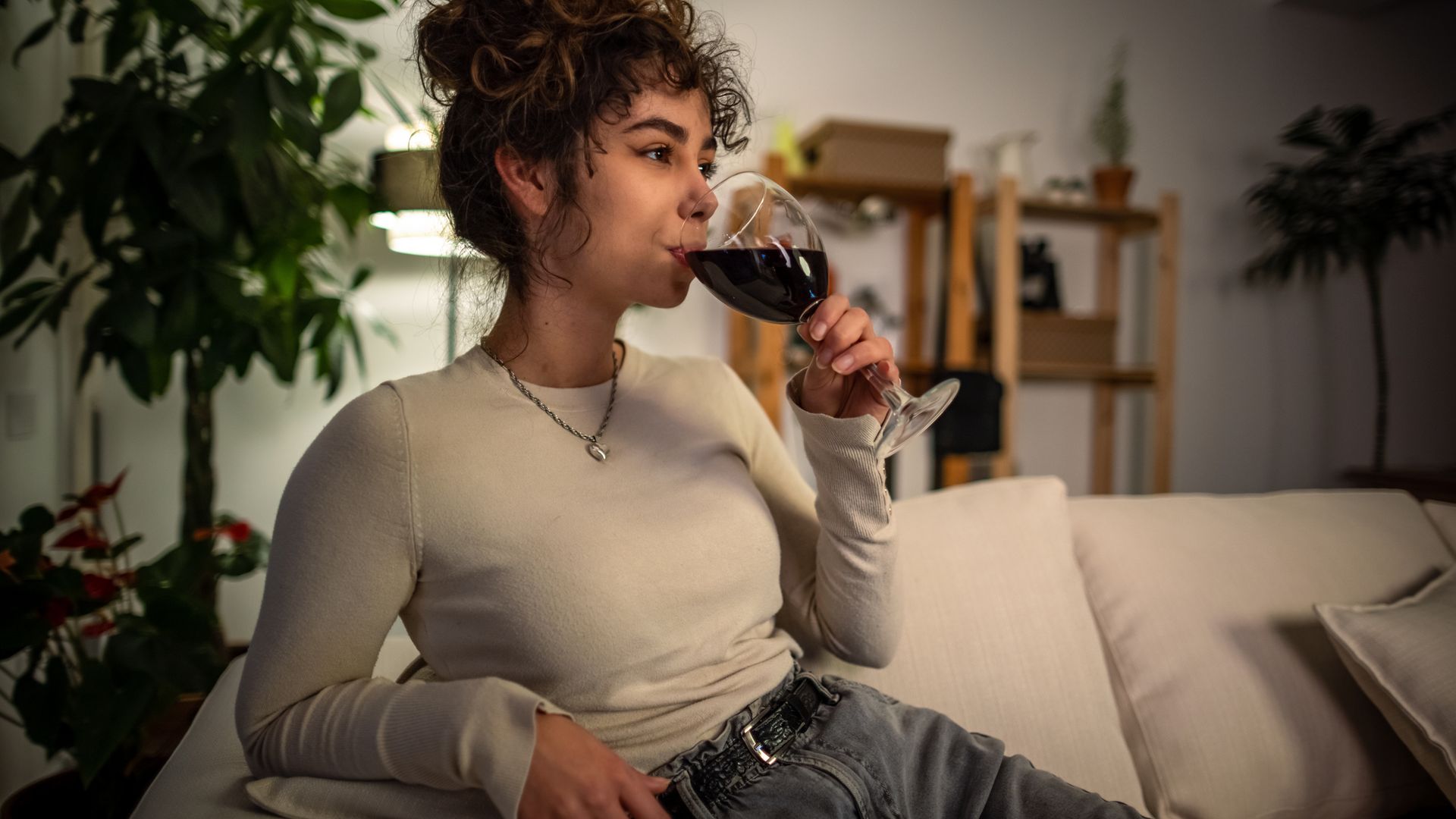 Shot of a young woman relaxing at night on sofa with a glass of wine.