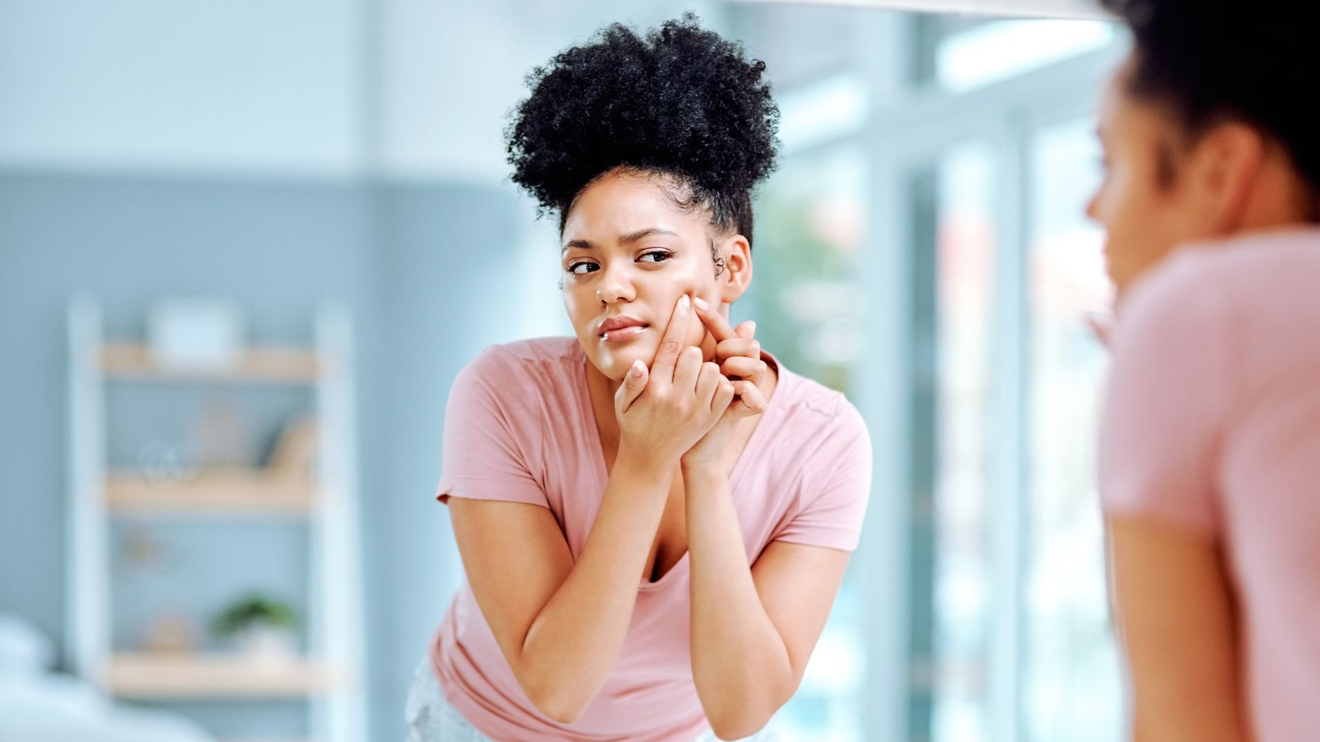 Shot of an attractive young woman squeezing a pimple on her face