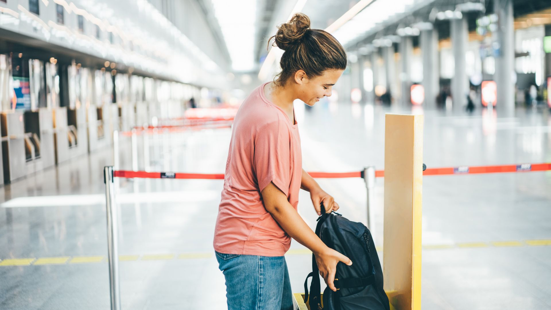 Woman checking size of her carry-on luggage at airport.