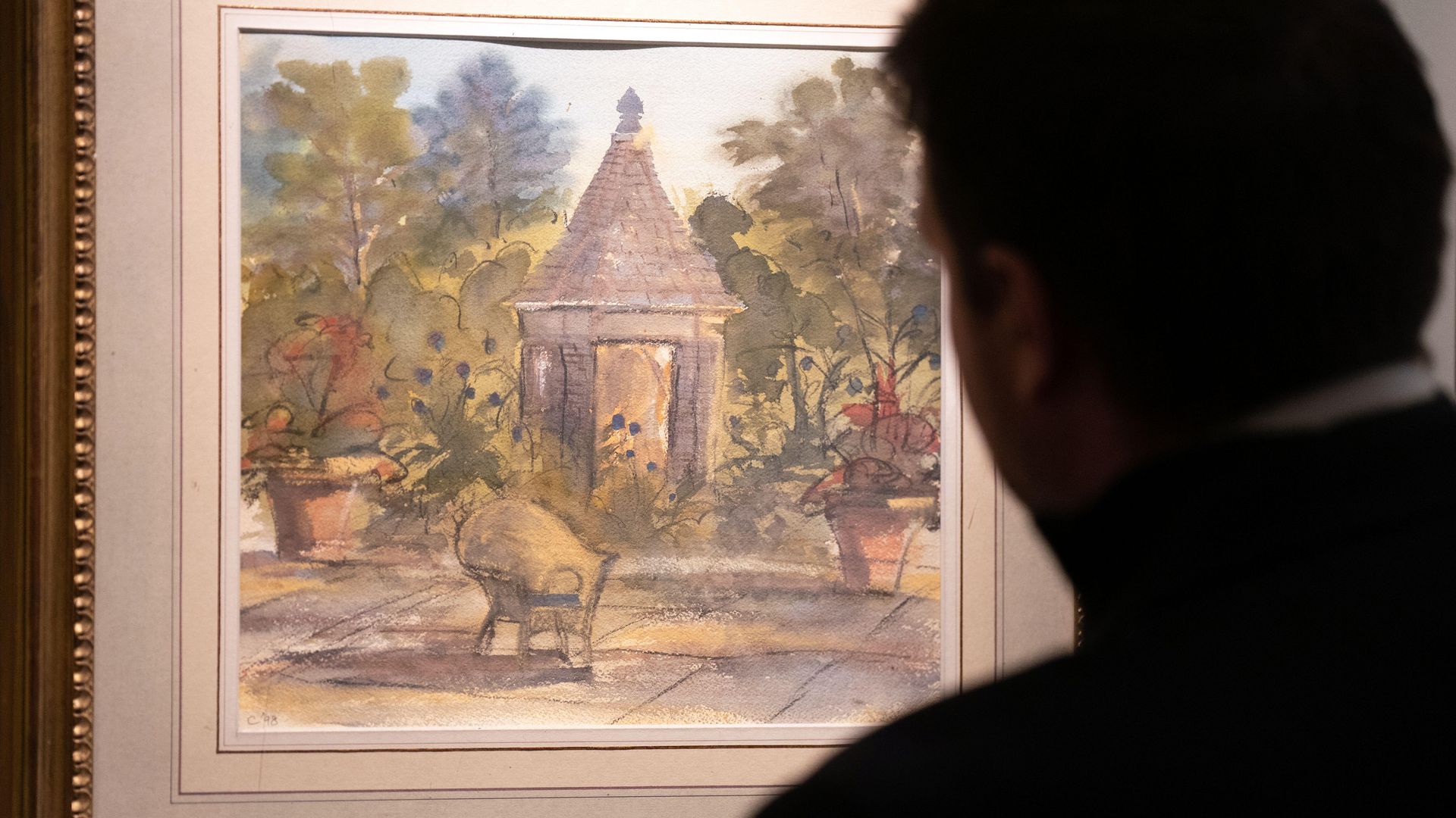 A man looking at a watercolour painting of a terrace at Highgrove by King Charles