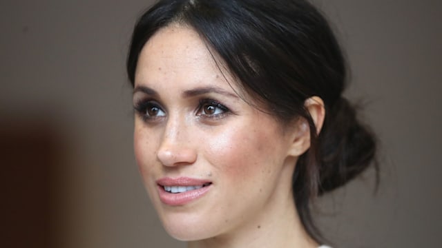 Meghan Markle with low bun and white top in Belfast