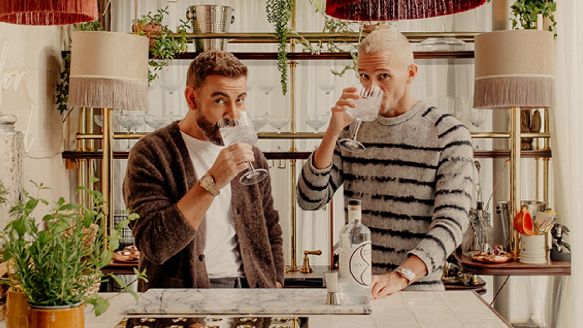 Ben Forster and his partner drinking in their kitchen under red lampshades