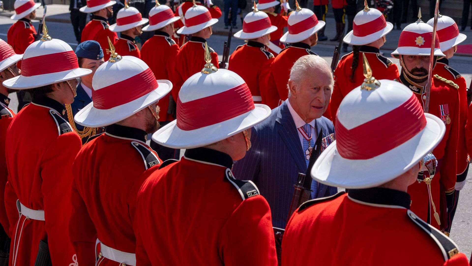 King Charles inspecting the honor guard, who wear red uniforms