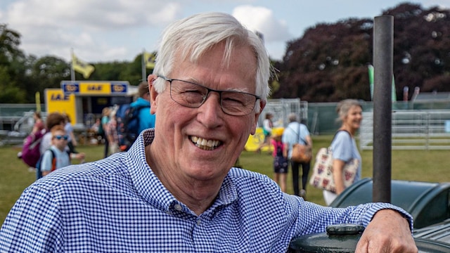 John Craven in a checkered shirt resting his arm on a tractor