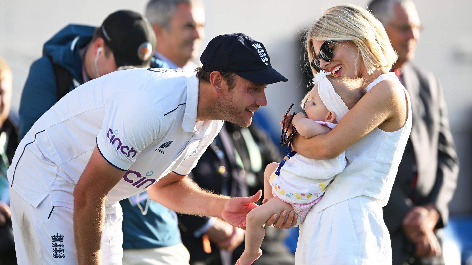 Mollie King holding her baby while her boyfriend Stuart Broad smiles at her 