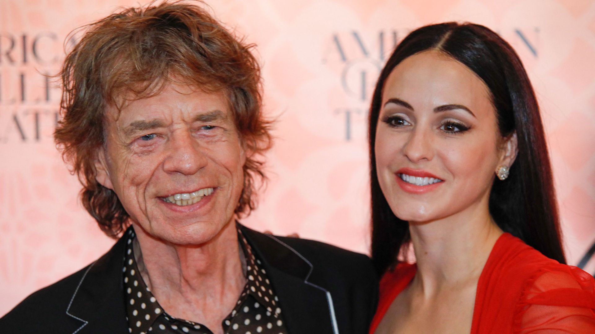 Mick Jagger and Melanie Hamrick smiling on a red carpet