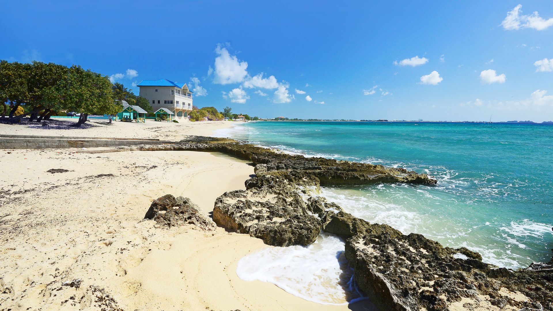 A beautiful tropical beach with clear turquoise waters, a sandy shore, and rocky outcrops