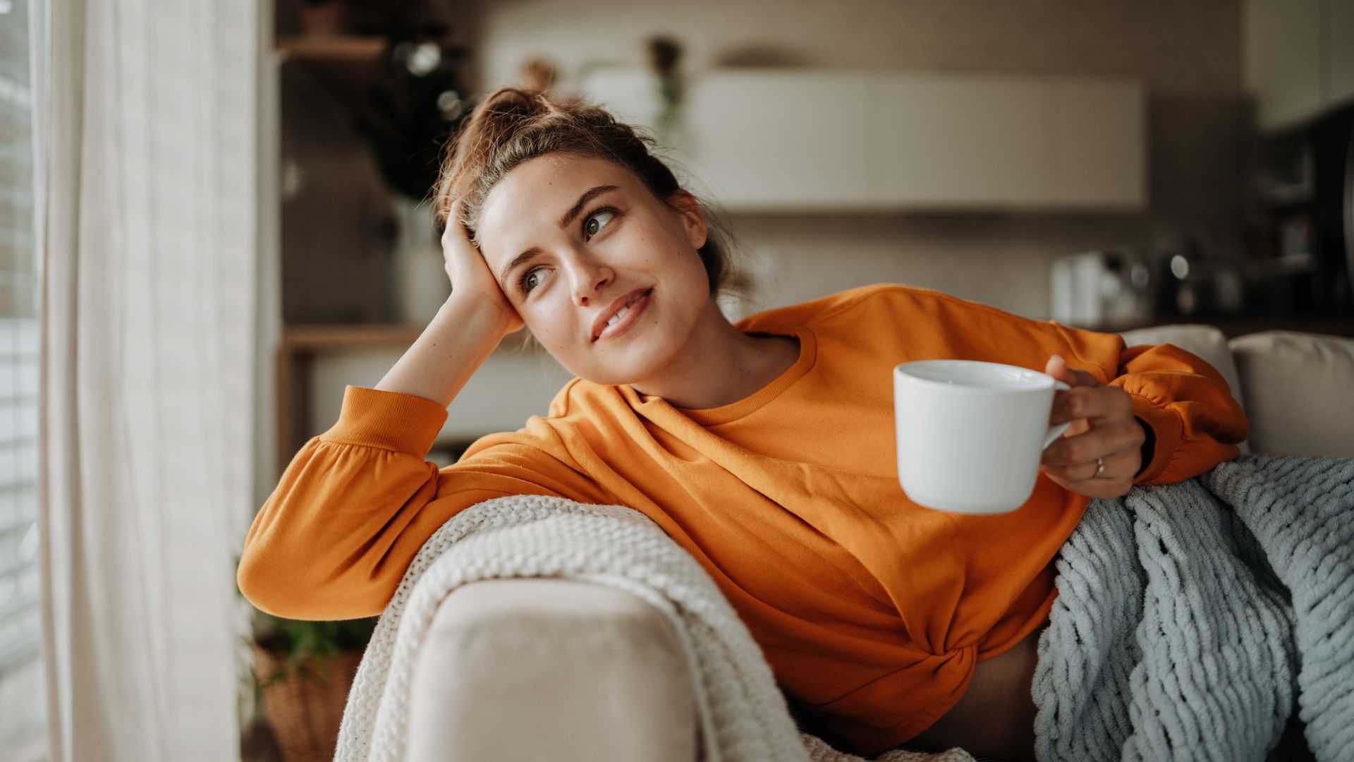 Young woman resting on sofa with cup of tea