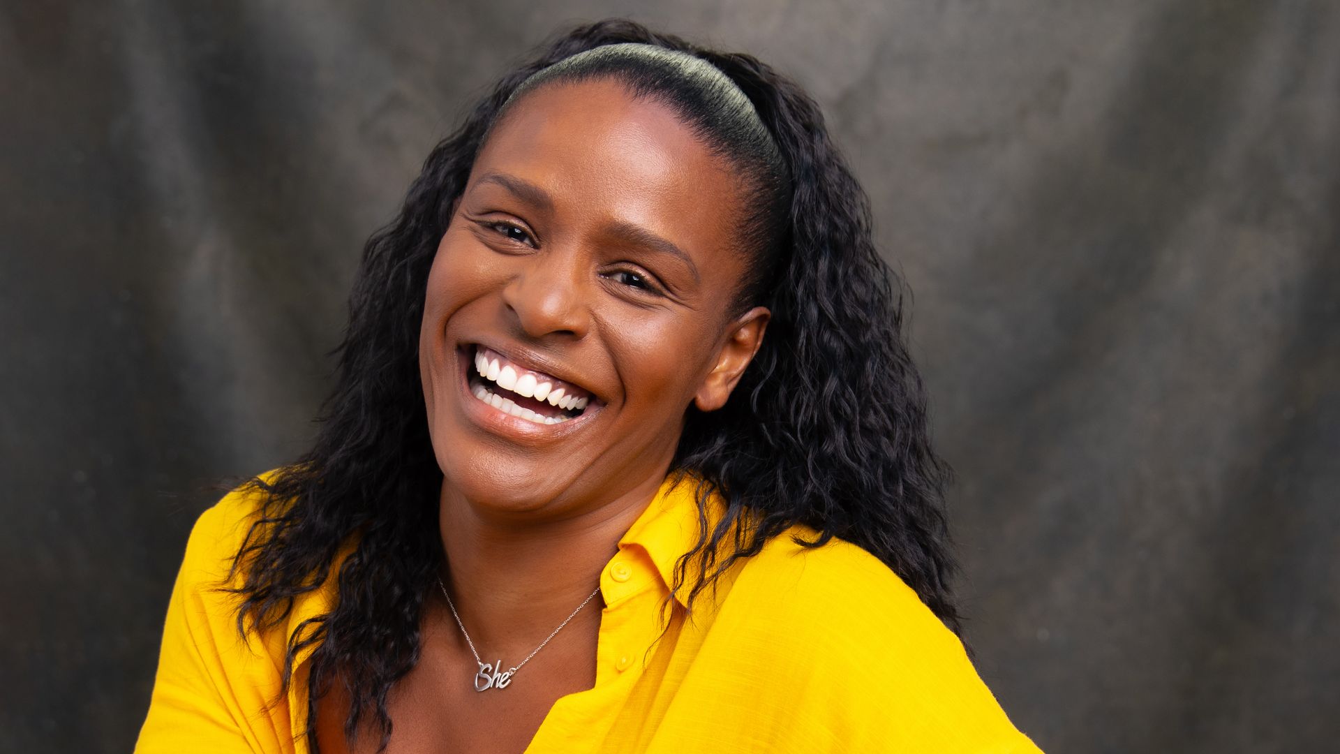 Black woman smiling in a yellow shirt