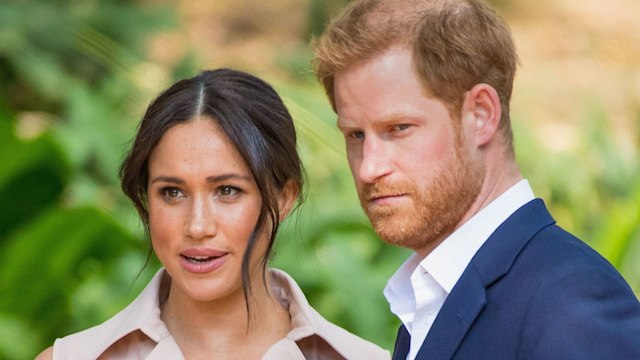 Prince Harry in a blue suit with Meghan Markle in a sleeveless dress