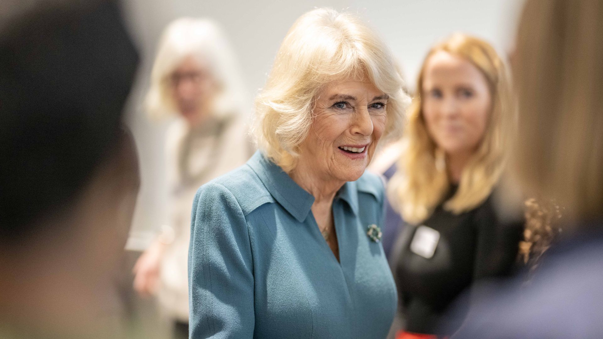 Queen Camilla wearing a green dress and smiling