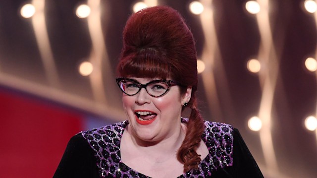 Woman holding envelope on stage at awards show