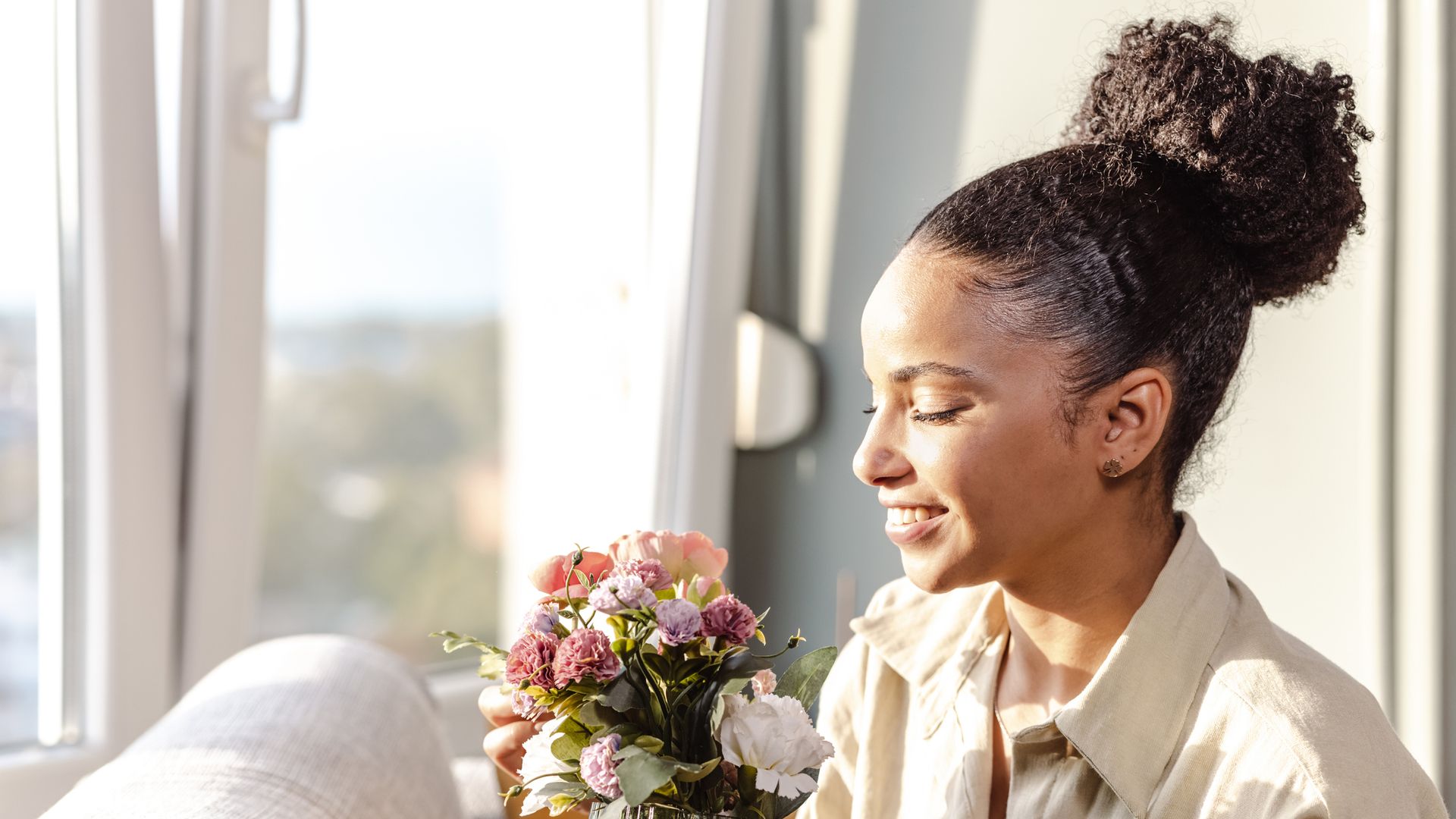 Beautiful young woman is at home, she is smiling and enjoying sunny afternoon at home