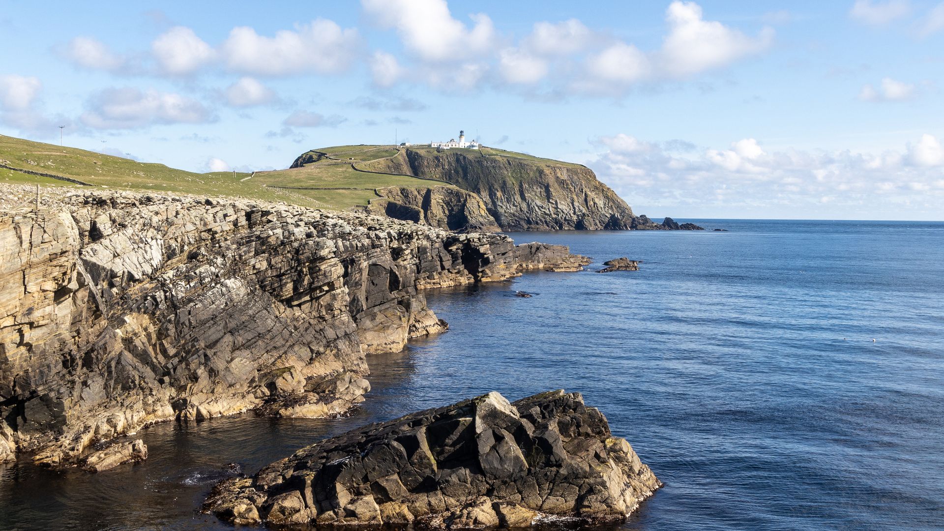 A shot of Sumburgh Head and its lighthouse with several cliffs