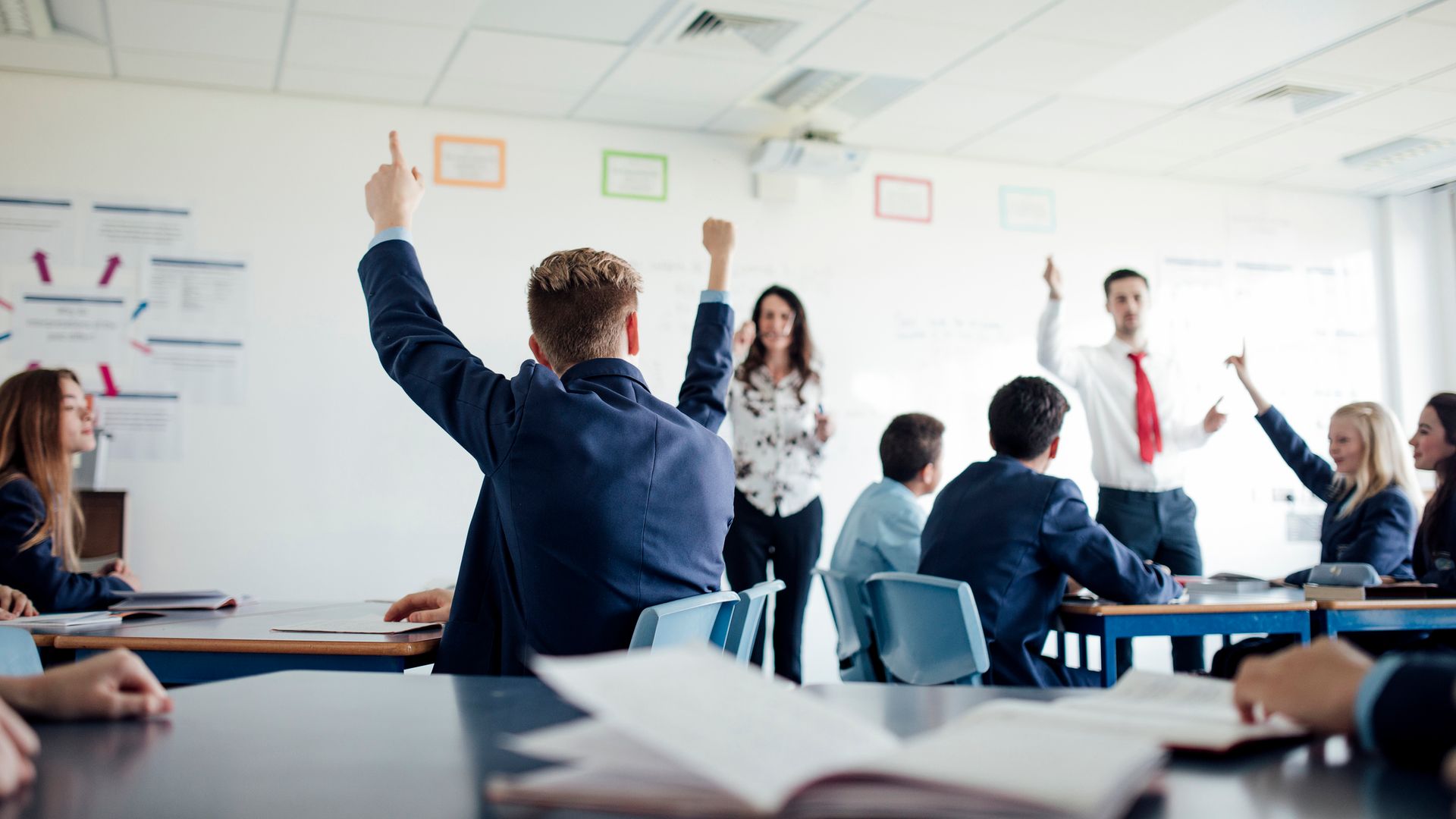 Teenage female student raising her hand to answer a question