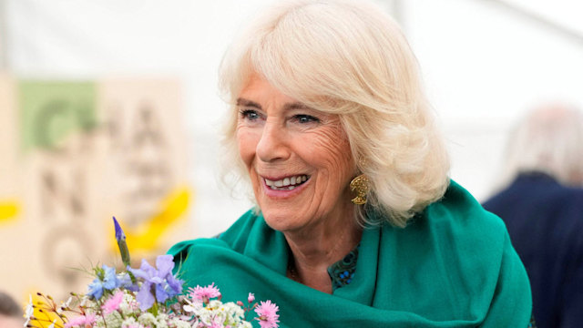 Queen Camilla smiling facing children