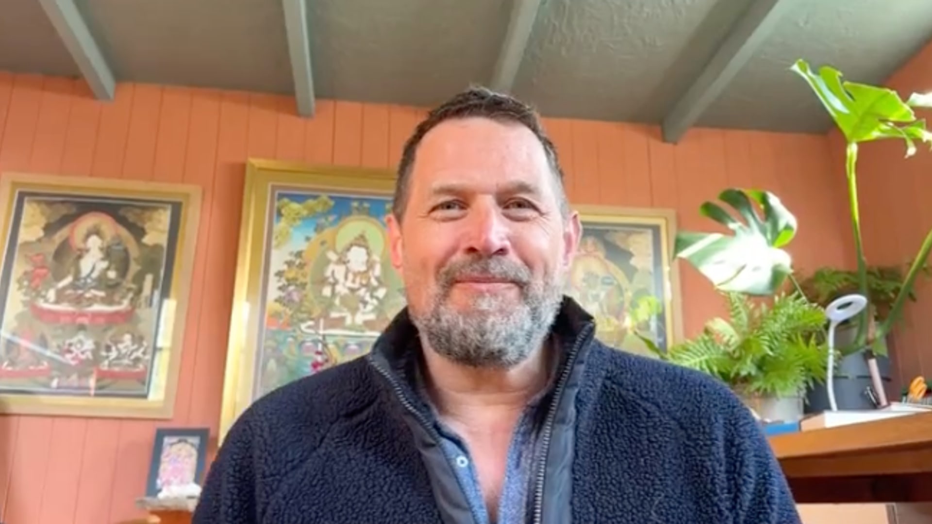 man in orange room with paintings on the wall