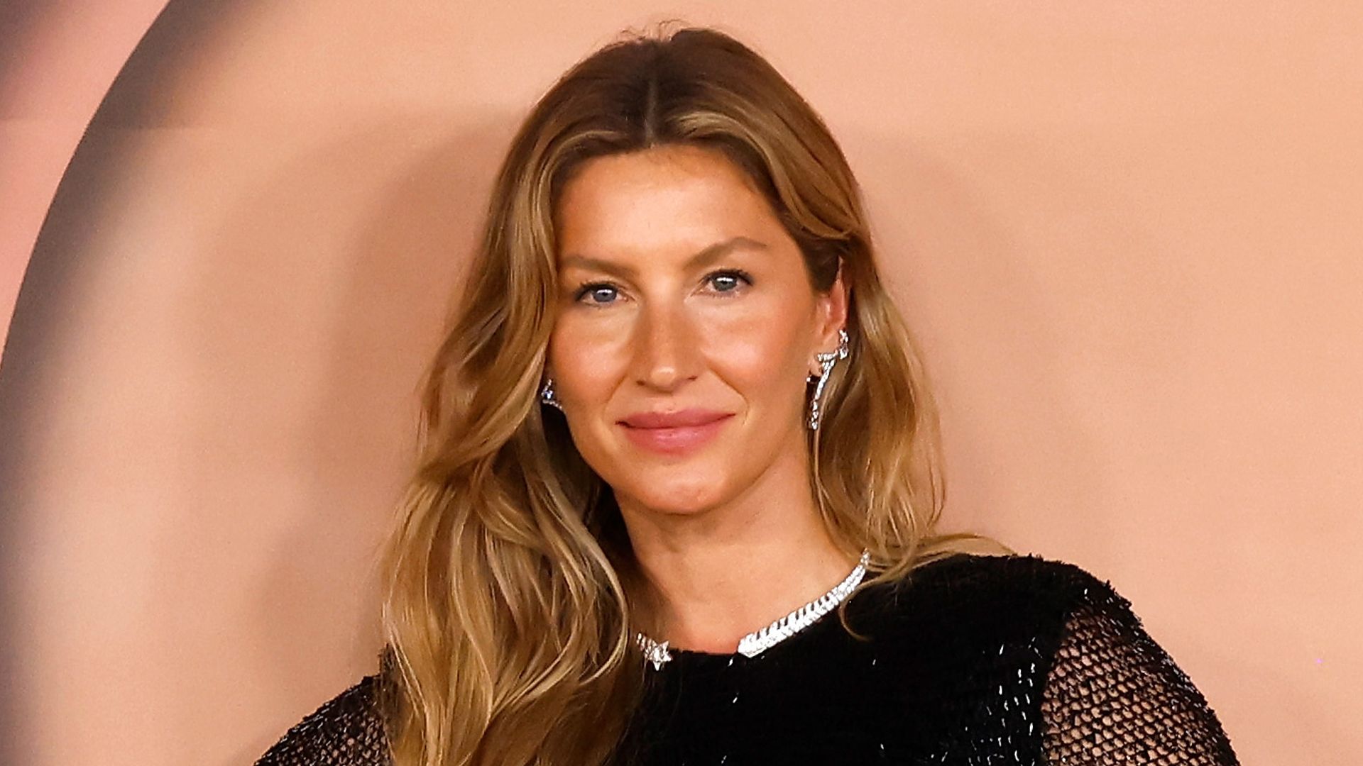 Gisele Bindchen wearing a black dress and crystal earrings
