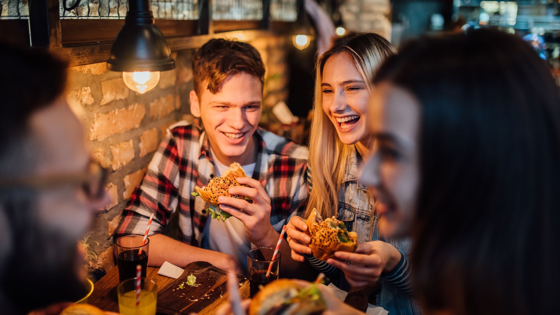 Happy young people eating hamburgers at the pub