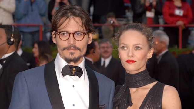 Johnny Depp wears a blue suit and Vanessa Paradis wears a sheer glittery black dress at the 77th Annual Academy Awards