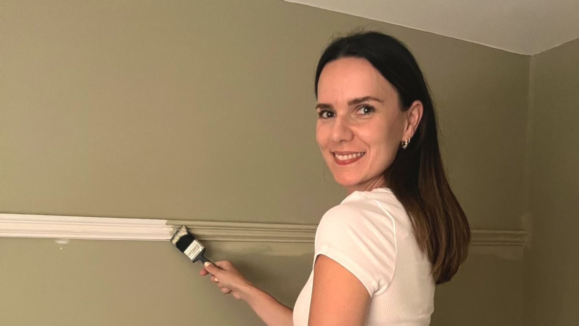 woman painting panelling on the wall 