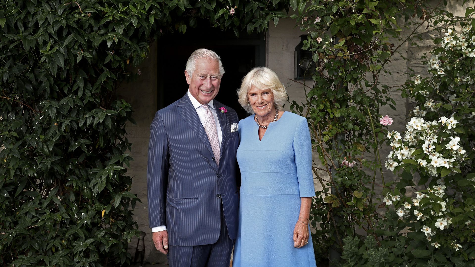 King Charles and Queen Camilla outside of a cottage