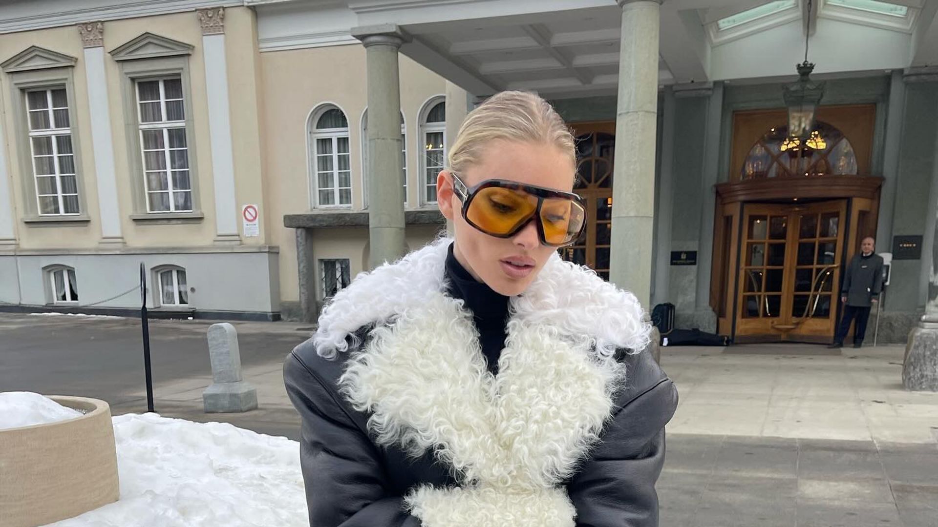 Influencer Elsa Hosk poses in a fluffy coat with orange sunglasses