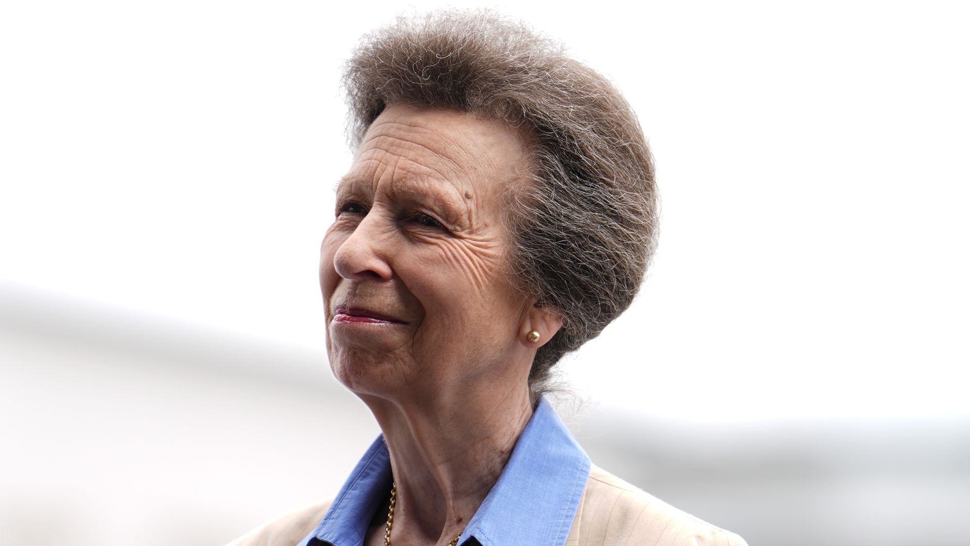 The Princess Royal smiling in neutral linen blazer and blue shirt