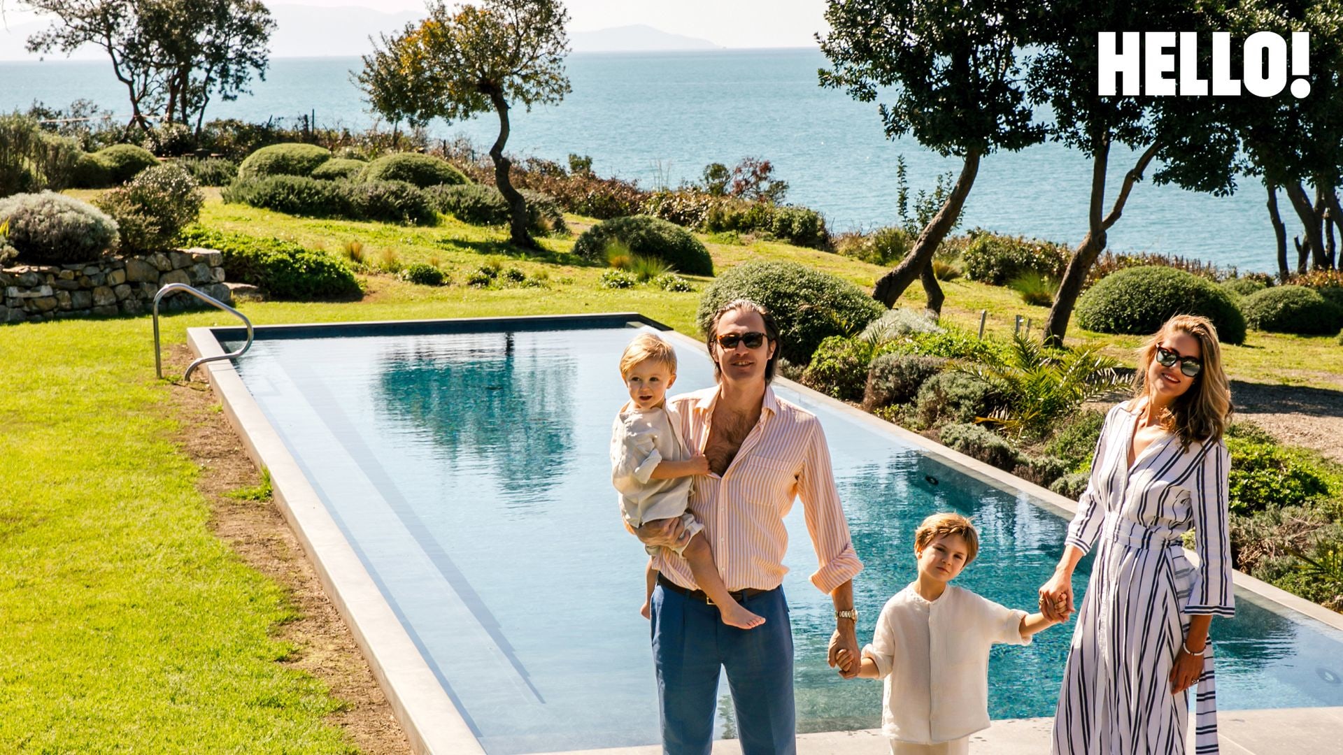 Massimiliano and Lucrezia with their sons, Egidio and Cristoforo, all holding hands posing by the pool 