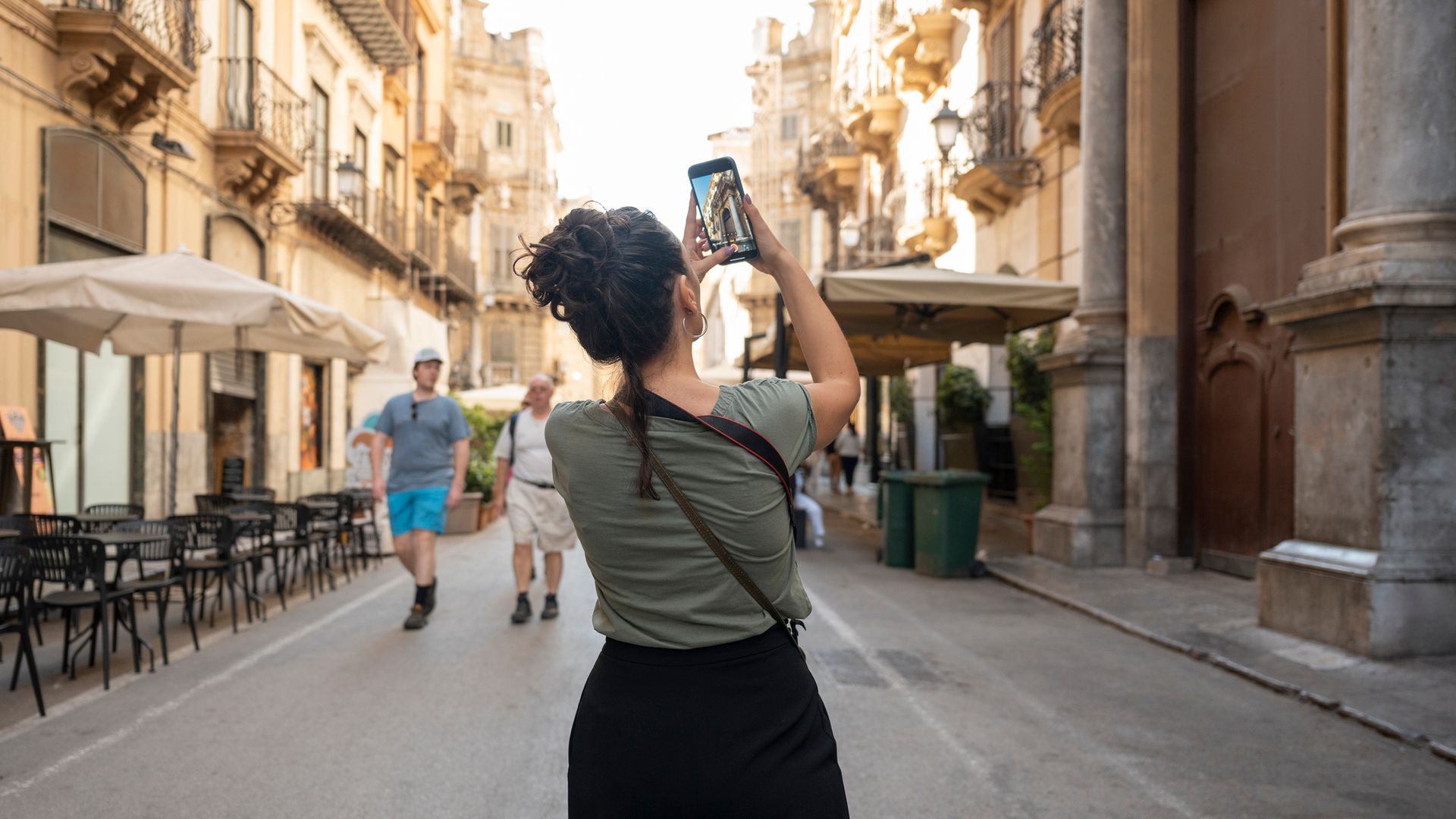 Rear view of tourist taking pictures in the old town of Palermo, Sicily, Italy
